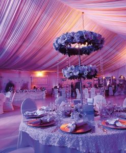 Imagen close up de una mesa preparada para un evento, con la indumentaria colocada según etiqueta y un centro de mesa alto con flores moradas, representando el diplomado en Organización de Eventos.