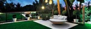 Imagen del diseño de jardín, con arbustos y árboles, área de estar, iluminación y en primer plano un sillón colgante que identifica la carrera de Diplomado en Diseño de Jardines.