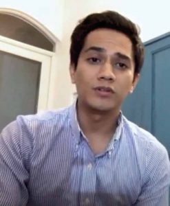 Hombre joven sentado hablando frente a una cámara