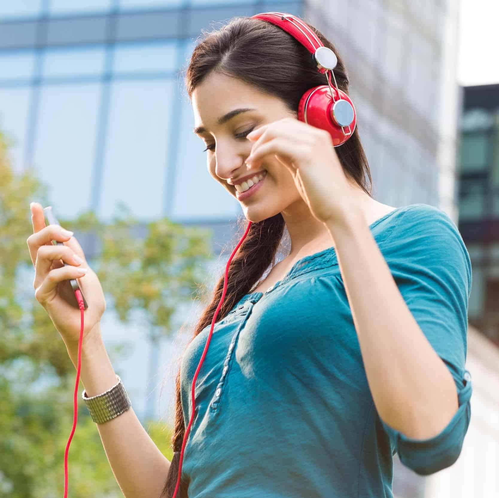 Una mujer sonriendo escuchando música en sus audífonos.