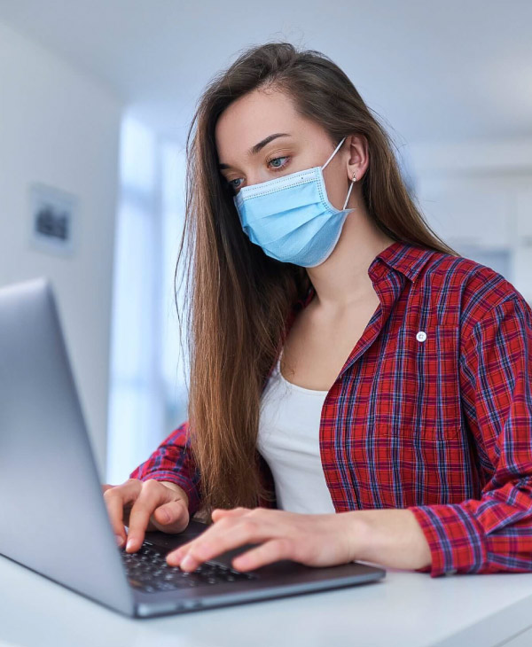 Una mujer con mascarilla, computadora