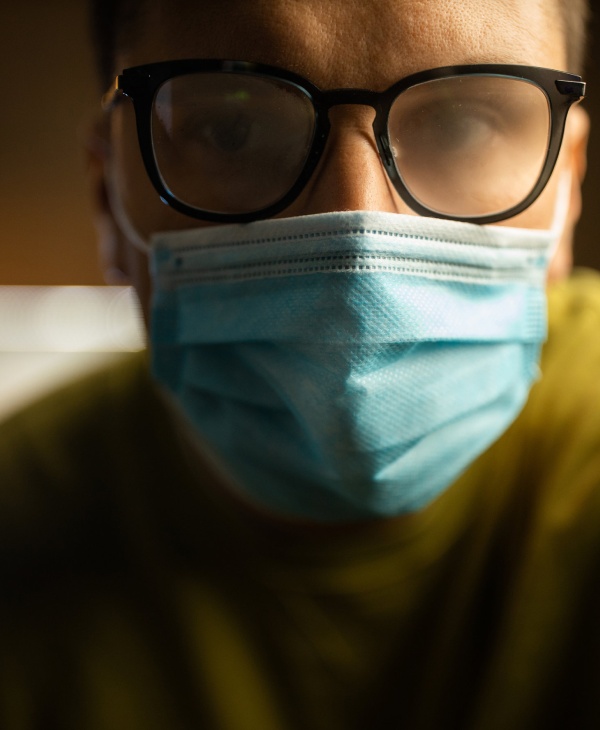 Un hombre, mascarilla azul, lentes, ojos.