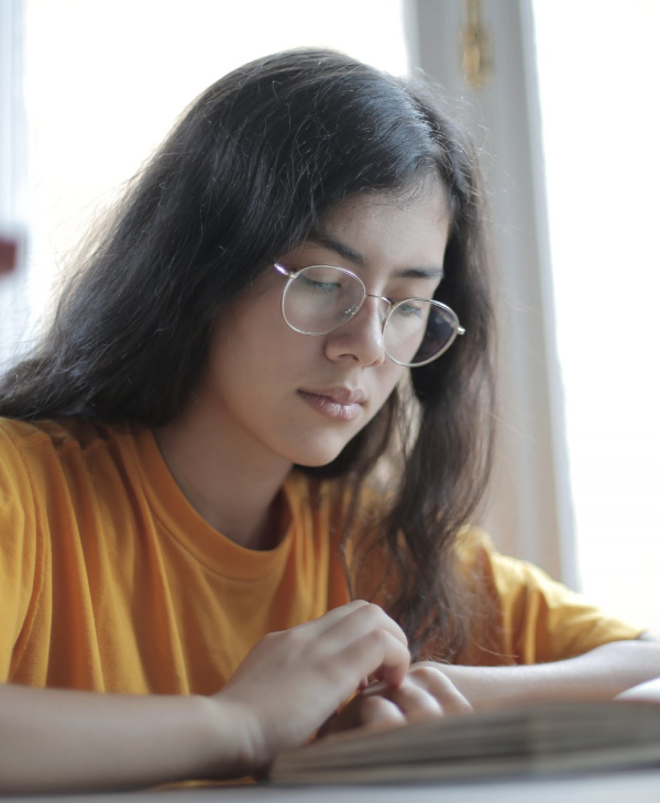 Una mujer con lentes, blusa amarilla.