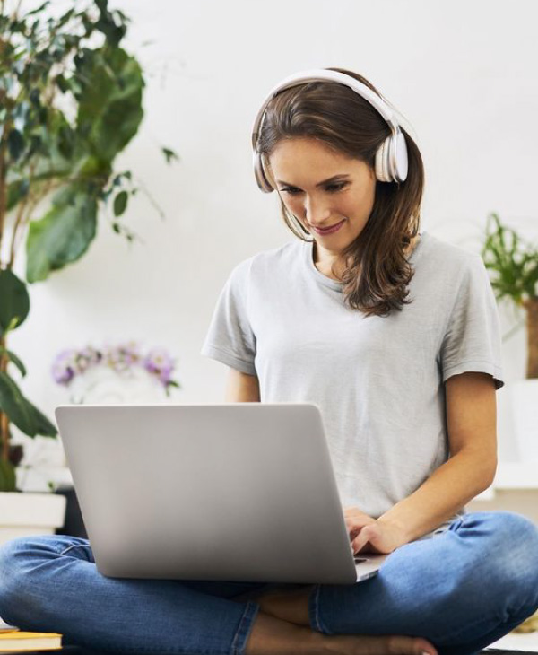 Una mujer con audifonos, computadora