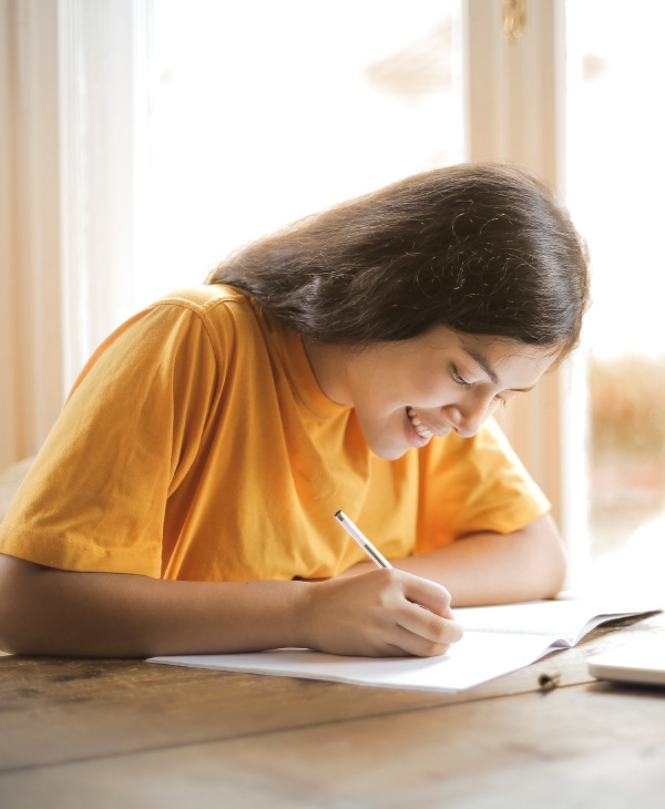 Una mujer con blusa naranja, lapicero, cuaderno, ventana
