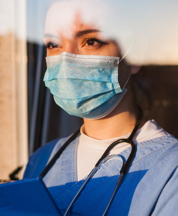 Una mujer vestida de celeste, mascarilla, estetoscopio