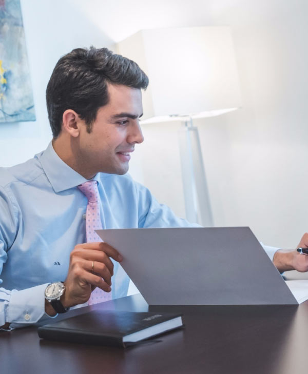 Un hombre con camisa celeste utilizando una tablet sentado frente a un escritorio